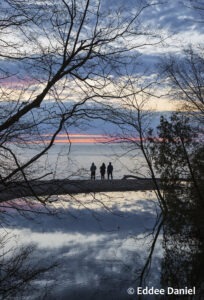 Three people silhouetted in front of a Lake Michigan sunrise
